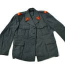 Vintage Swiss military wool jacket in grey with chest and side pockets, featuring red insignia patches on shoulders.