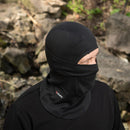 Person wearing black M-TAC military style tactical balaclava outdoors with rocky background, lightweight and warm face mask