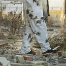 Person wearing A.Blochl German army style snow camo pants with black camouflage spots in outdoor rubble setting