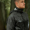 Man wearing waterproof military-style rain jacket with hood in outdoor forest setting during rain