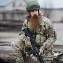 Soldier wearing Leo Kohler military tactical smock jacket in multicam camouflage holding a rifle outdoors