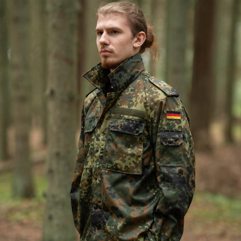 Man wearing Leo Kohler tactical military shirt in flecktarn camouflage with German flag patch in forest setting