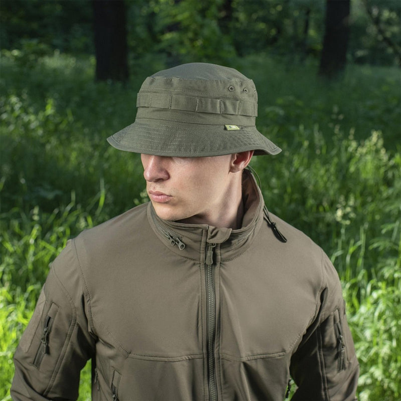 Man wearing M-TAC olive green military style boonie hat and tactical jacket in outdoor forest setting