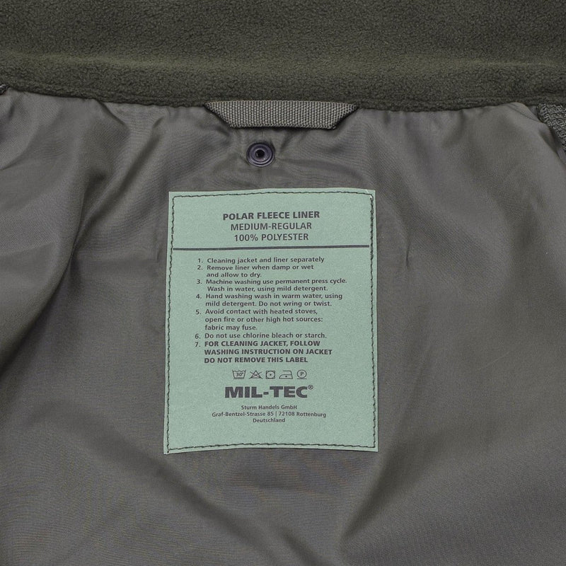 Close-up of MIL-TEC polar fleece liner label inside woodland camo winter jacket, showing care instructions and material details.