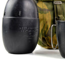 Original British Army black canteen with warning text, accompanied by woodland camouflage pouch and metal mug handle visible