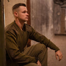 Man wearing original Italian army olive green wool V-neck Commando jumper sitting indoors against a wall