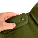 Close-up of hand holding the olive green epaulet with button on original Czech M85 military field jacket collar